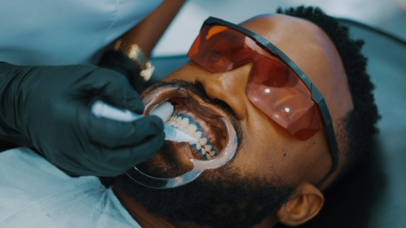 a man getting his teeth brushed by a dentist